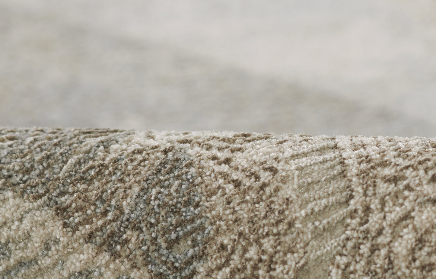 Close-up of a beige-taupe & blue woven rug with plush loop pile and subtle geometric texture.