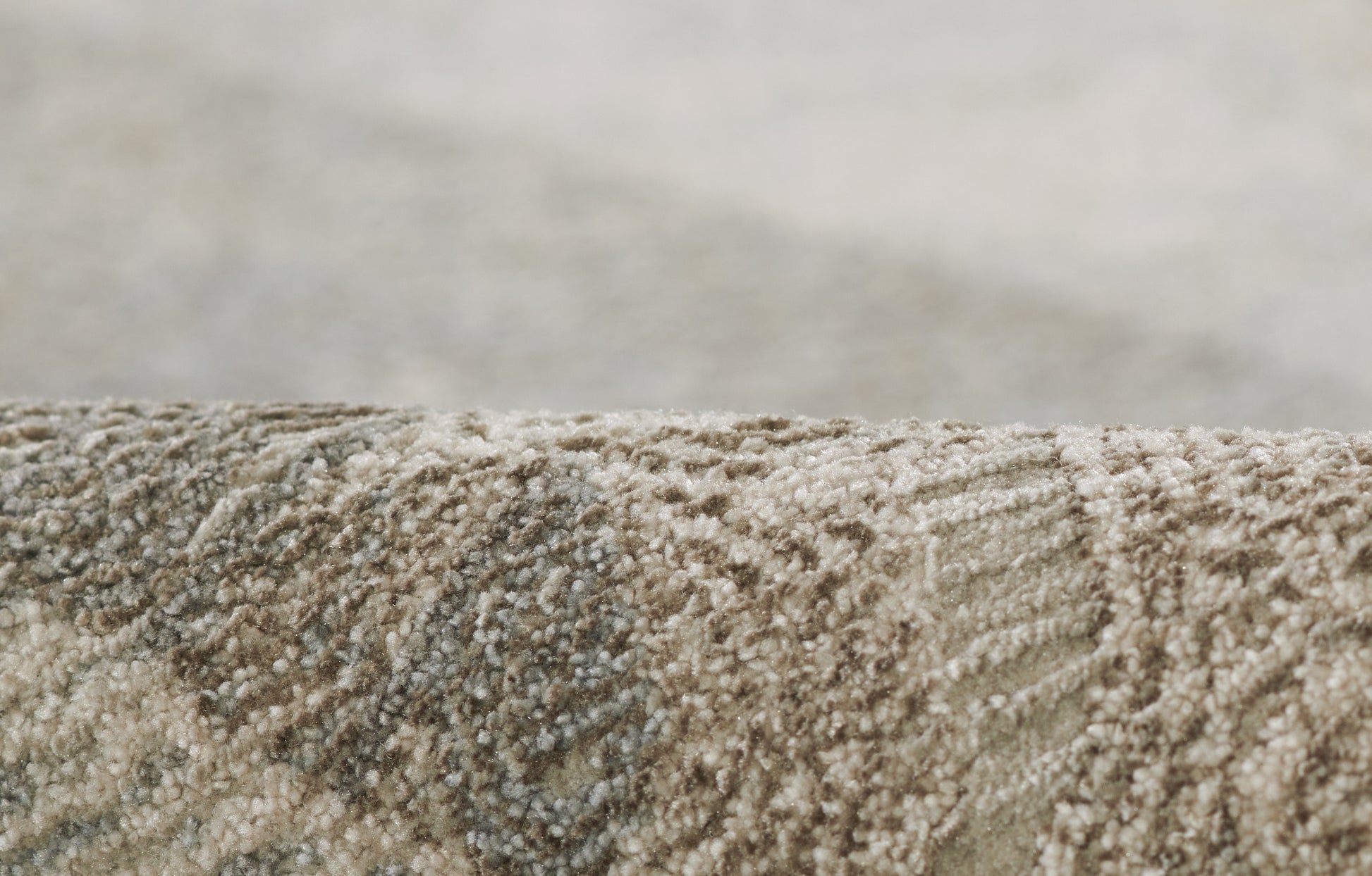 Close-up of beige-brown textured rug with loop pile and abstract circular pattern.