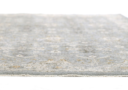 Blue-gray distressed area rug close-up with soft textured pile and faded circular pattern, edge visible.