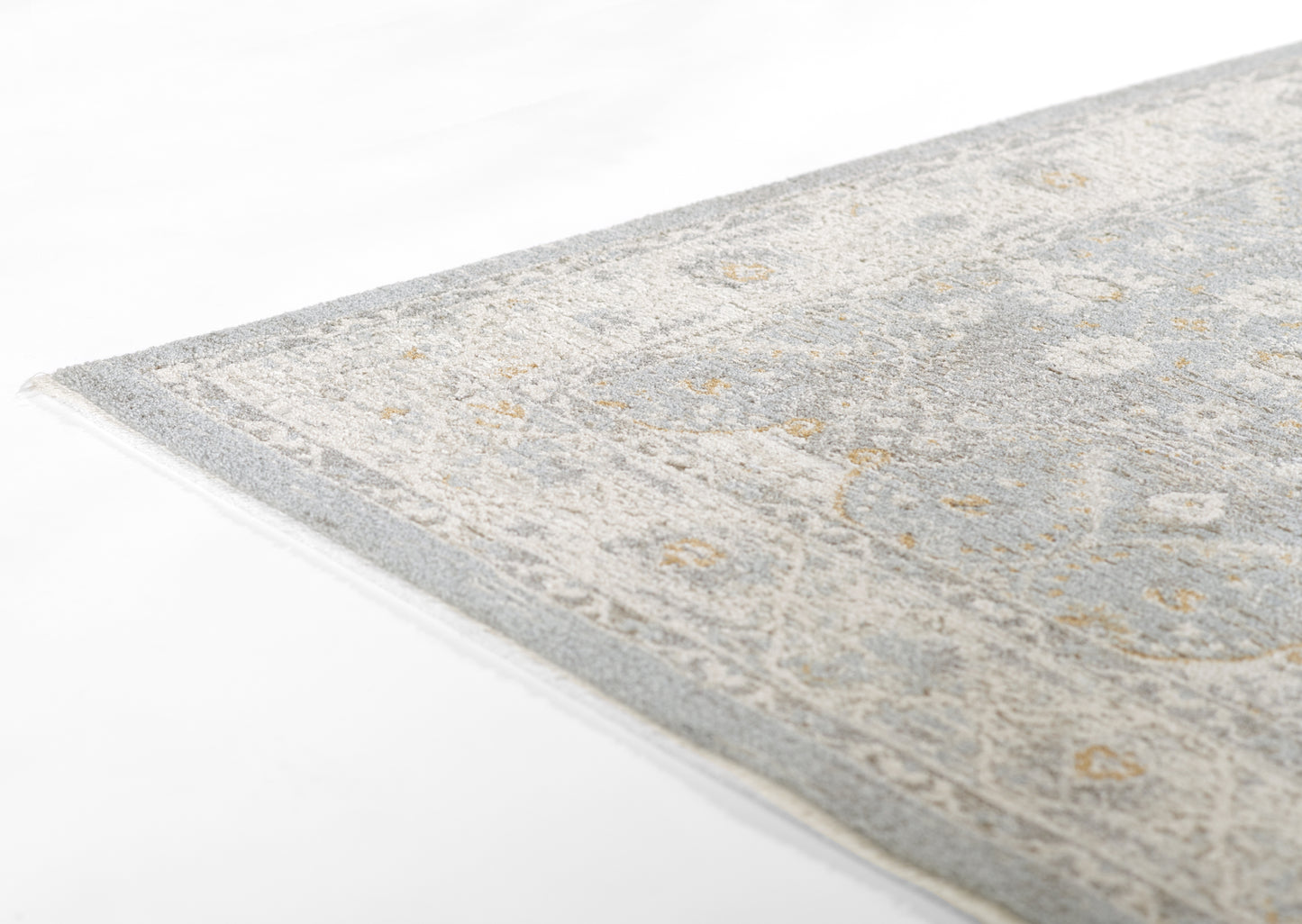 Blue-gray oriental-style rug with ivory and gold motifs, woven texture and visible edge.