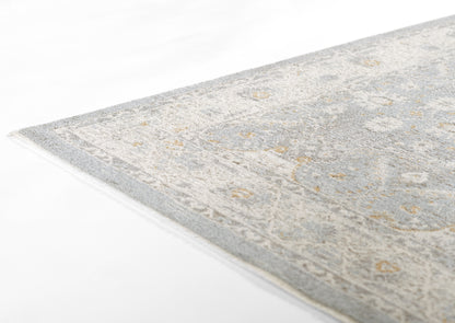 Blue-gray oriental-style rug with ivory and gold motifs, woven texture and visible edge.