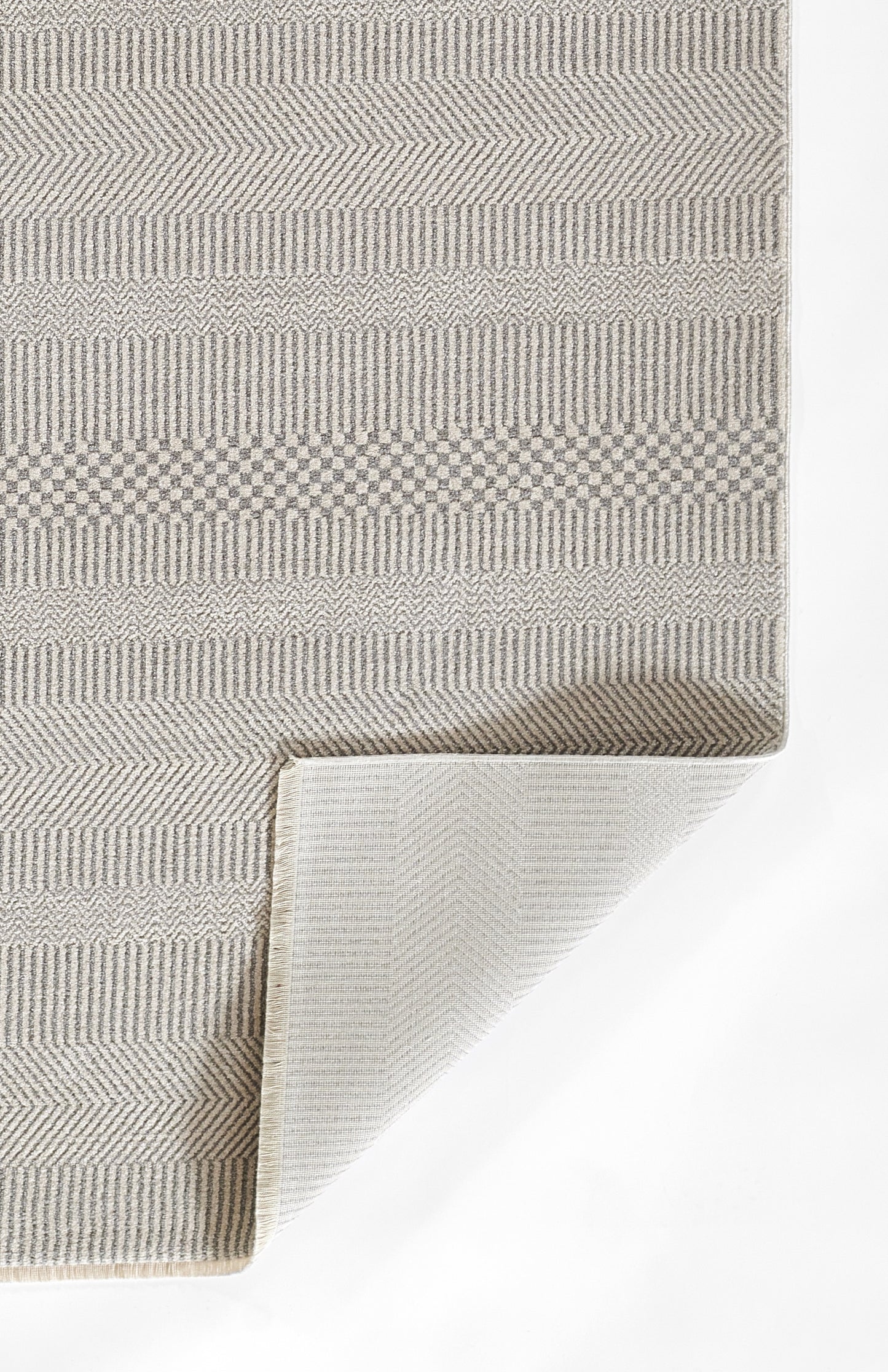 Neutral woven area rug in beige-gray with chevron and stripe patterns; soft texture, folded corner shows lighter back.