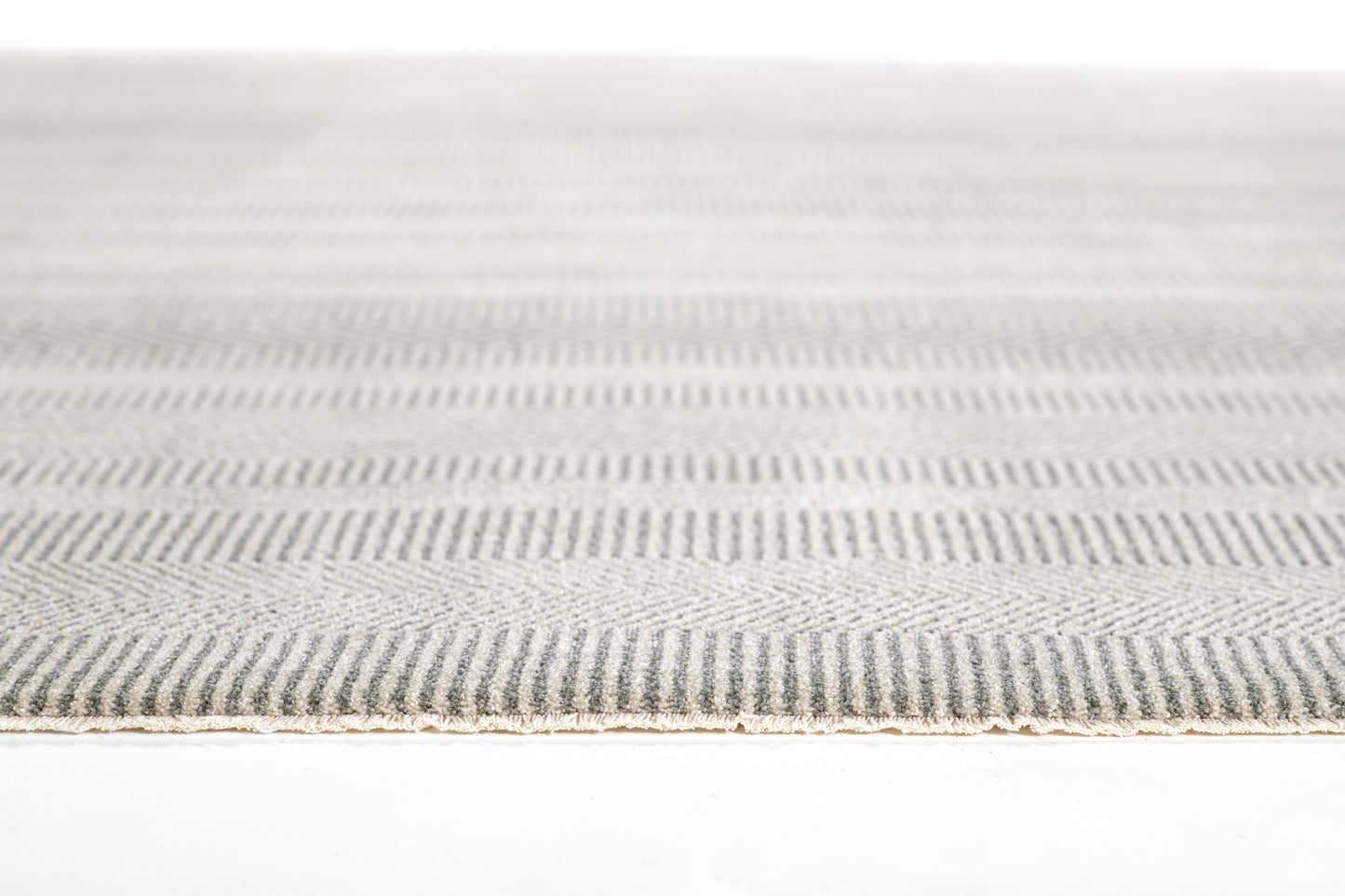 Close-up of a gray striped woven rug with a beige edge trim.