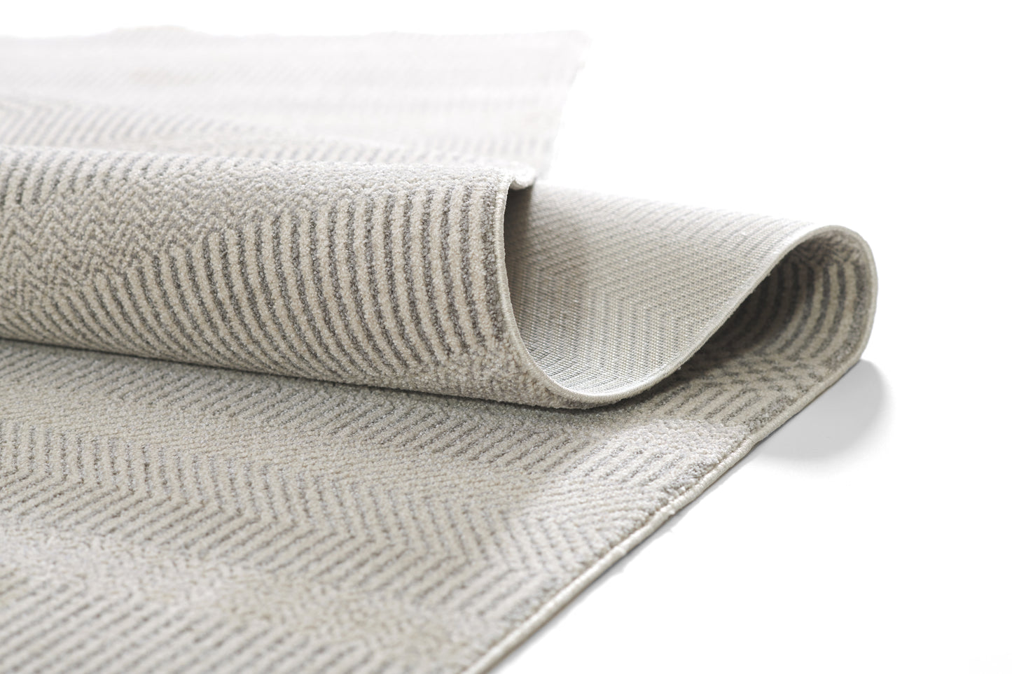 Beige-gray herringbone woven rug, rolled corner reveals soft texture, neutral living room decor.