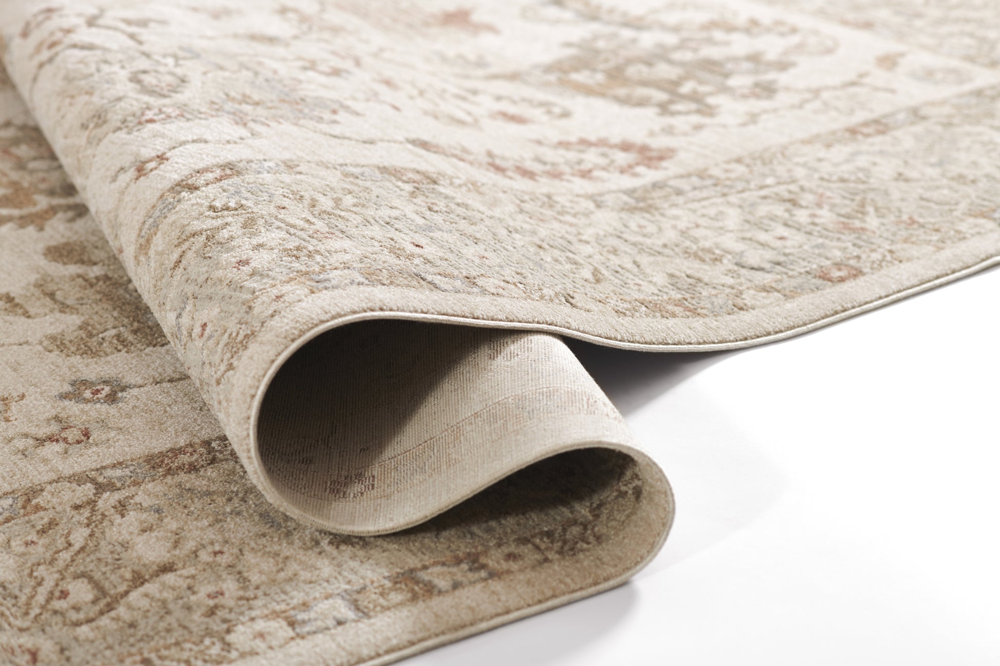 Beige patterned area rug with subtle vintage motif, rolled edge showing soft pile and neutral tones.