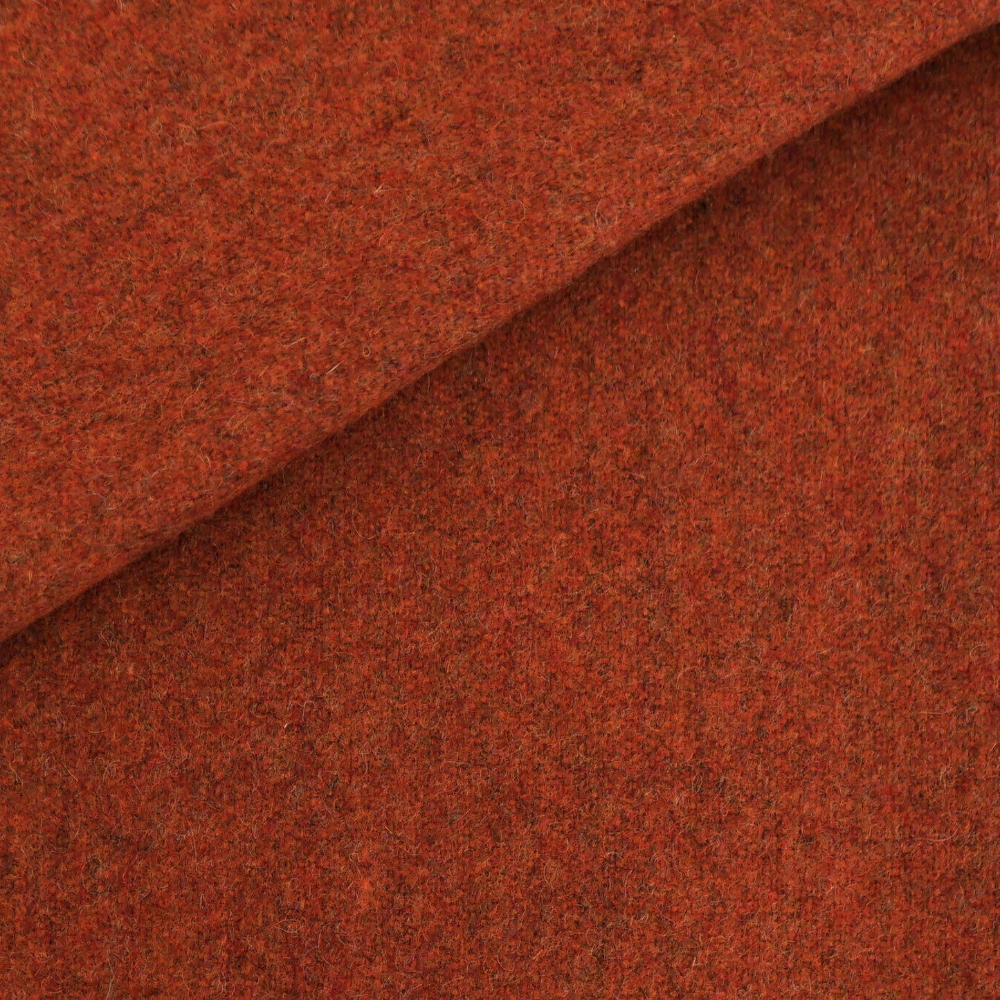 Rust-orange wool fabric with a fuzzy texture and diagonal fold; ideal for coats or jackets.