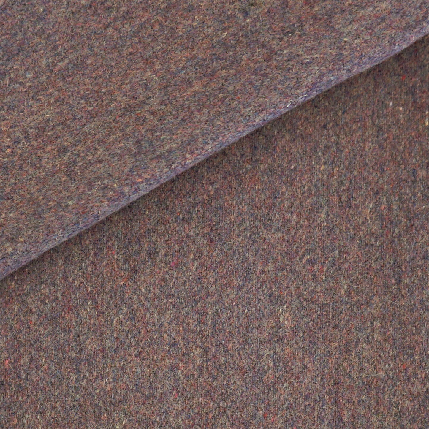 Brown tweed wool fabric close-up with multicolor flecks and folded edge