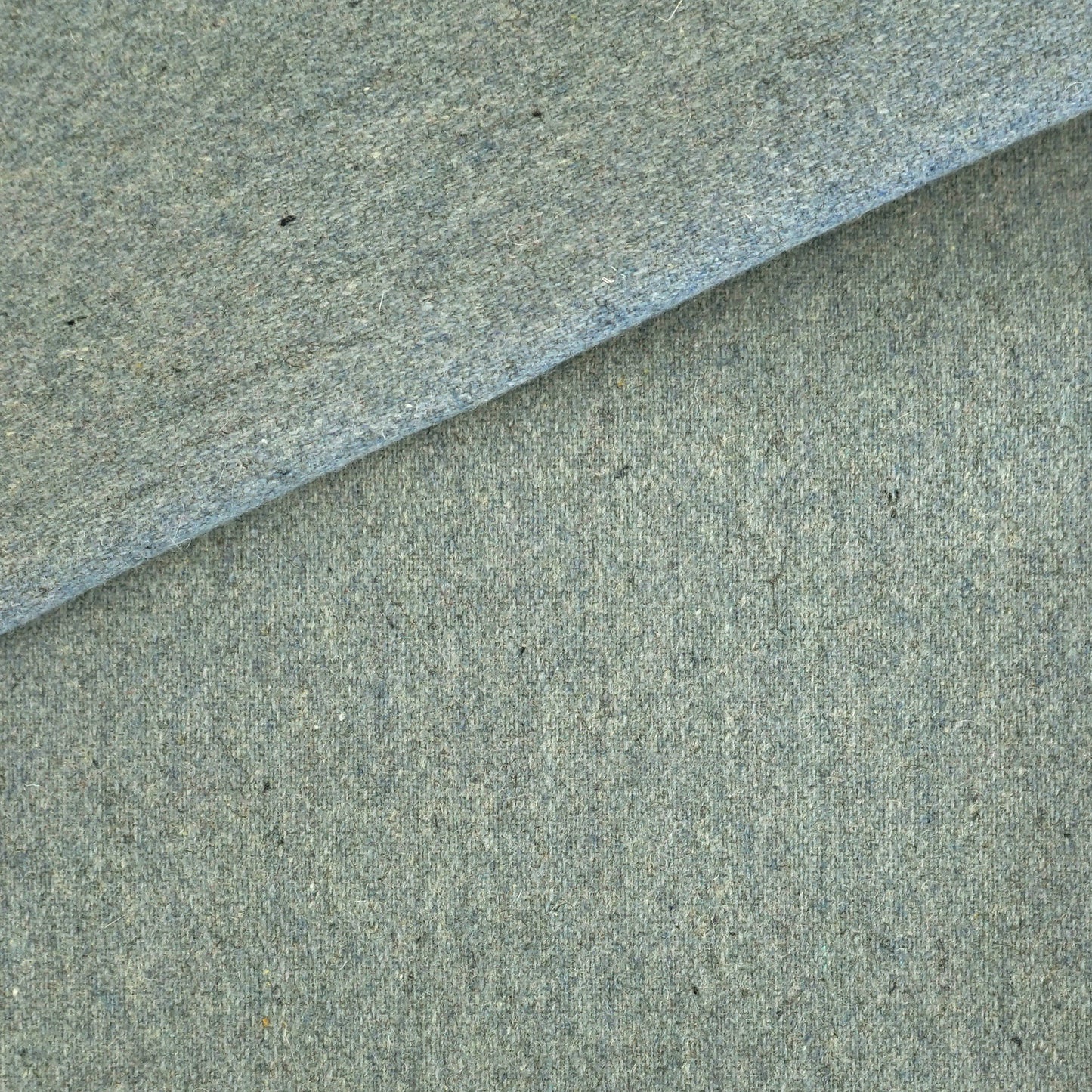 Blue wool fabric close-up with soft felt-like texture and folded edge.