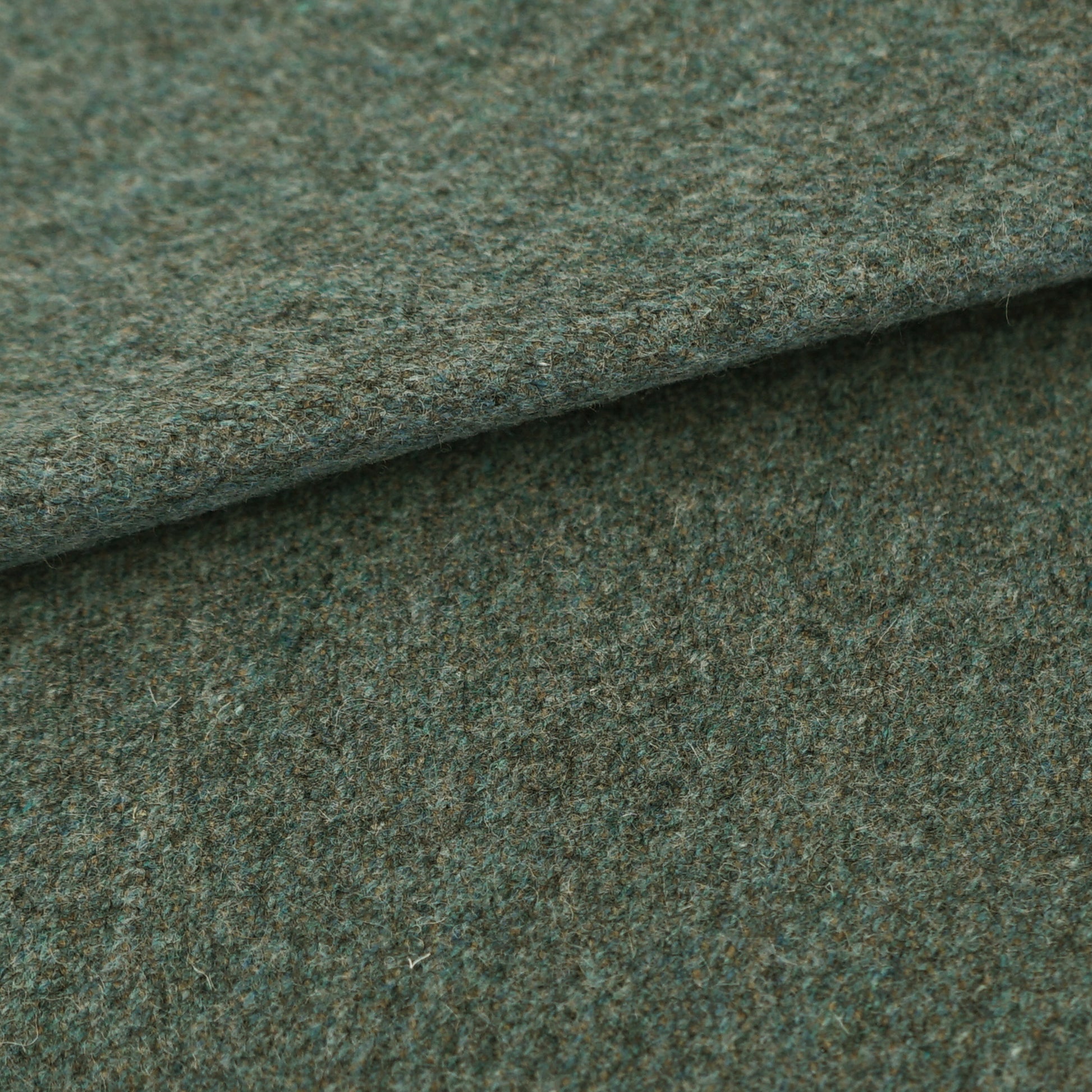 Close-up of blue wool fabric with a folded edge, showing a speckled, textured tweed-like surface.