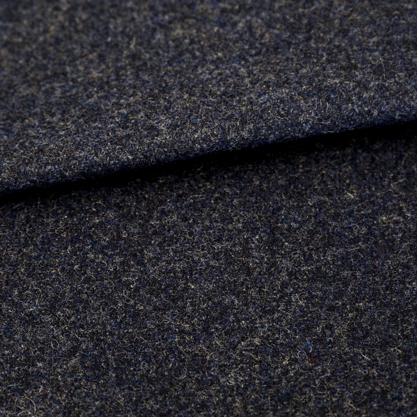 Dark blue wool fabric close-up with subtle texture and folded edge; suitable for suiting/coat material.