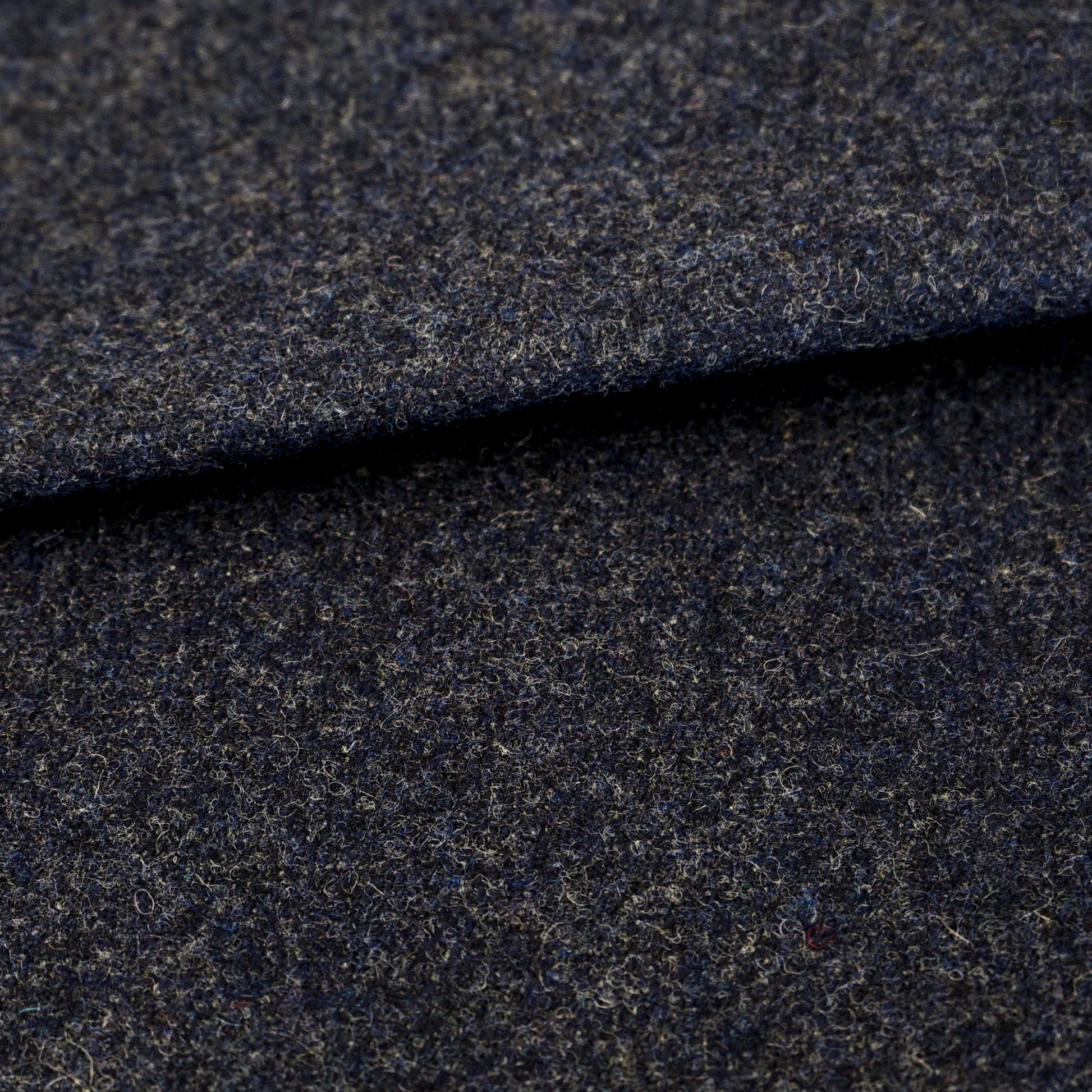 Dark blue wool fabric close-up with subtle texture and folded edge; suitable for suiting/coat material.