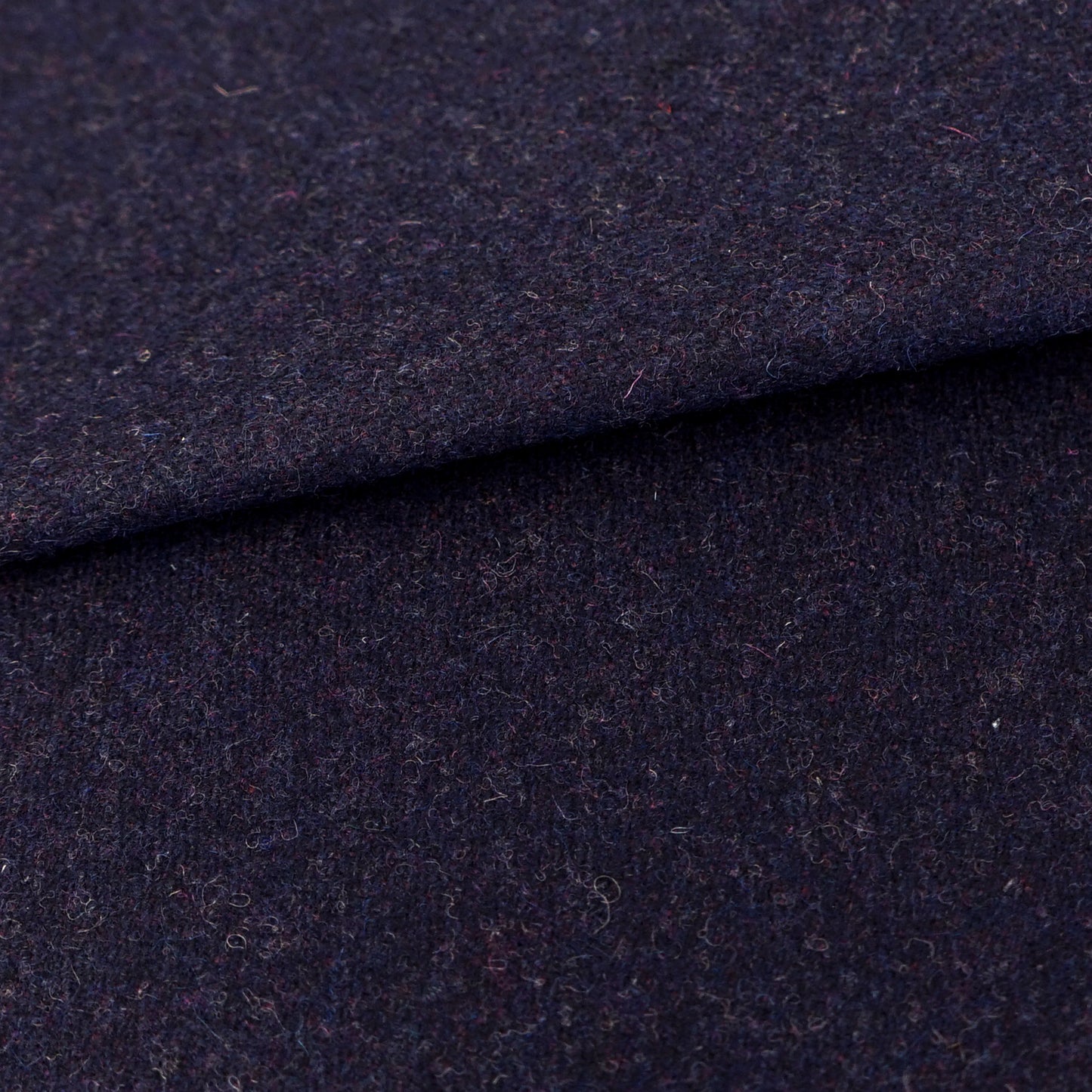 Dark navy wool fabric close-up with a folded edge and soft texture, ideal for coats or suits.