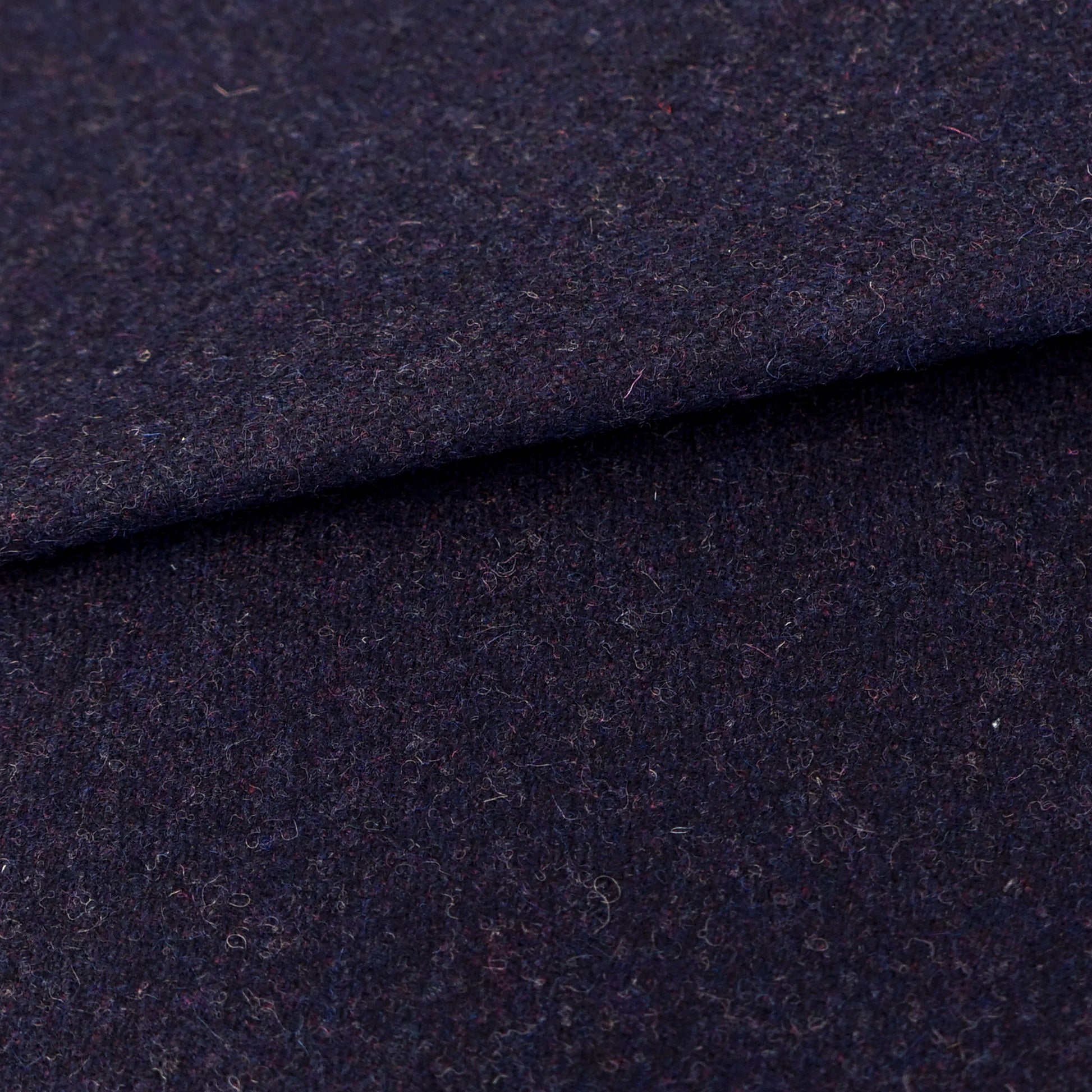 Dark navy wool fabric close-up with a folded edge and soft texture, ideal for coats or suits.