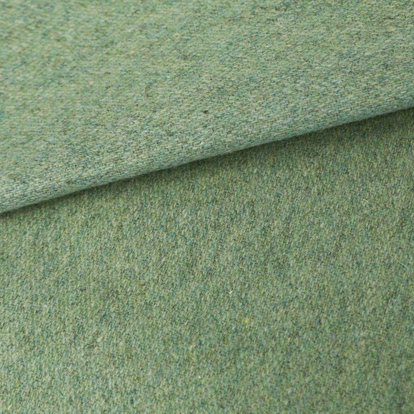 Sage green wool fabric roll with folded edge and plain textured weave.