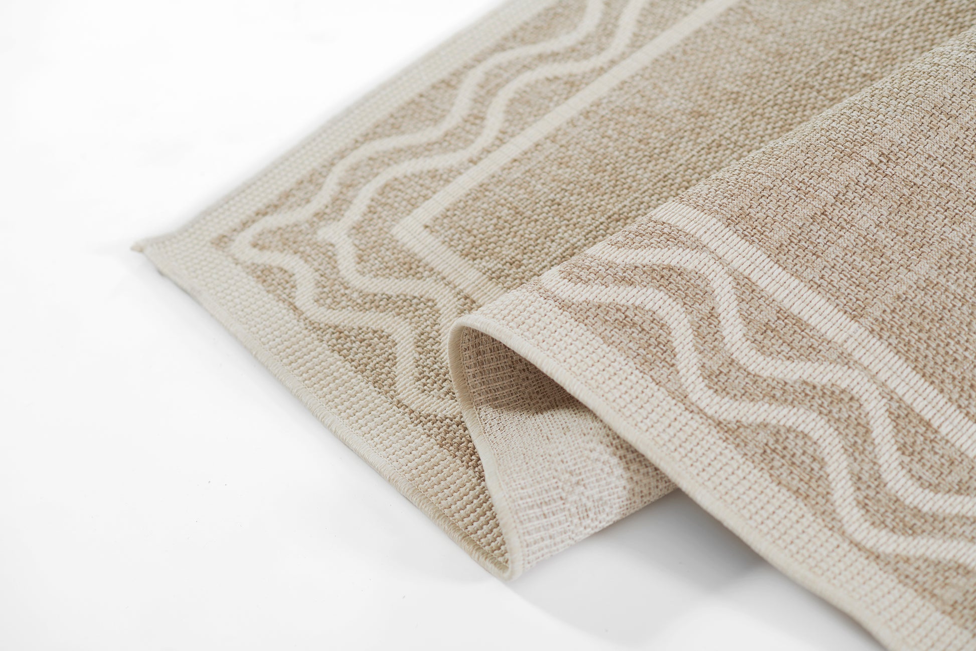 Beige woven rug with cream wavy border; folded corner reveals textured, soft fabric.