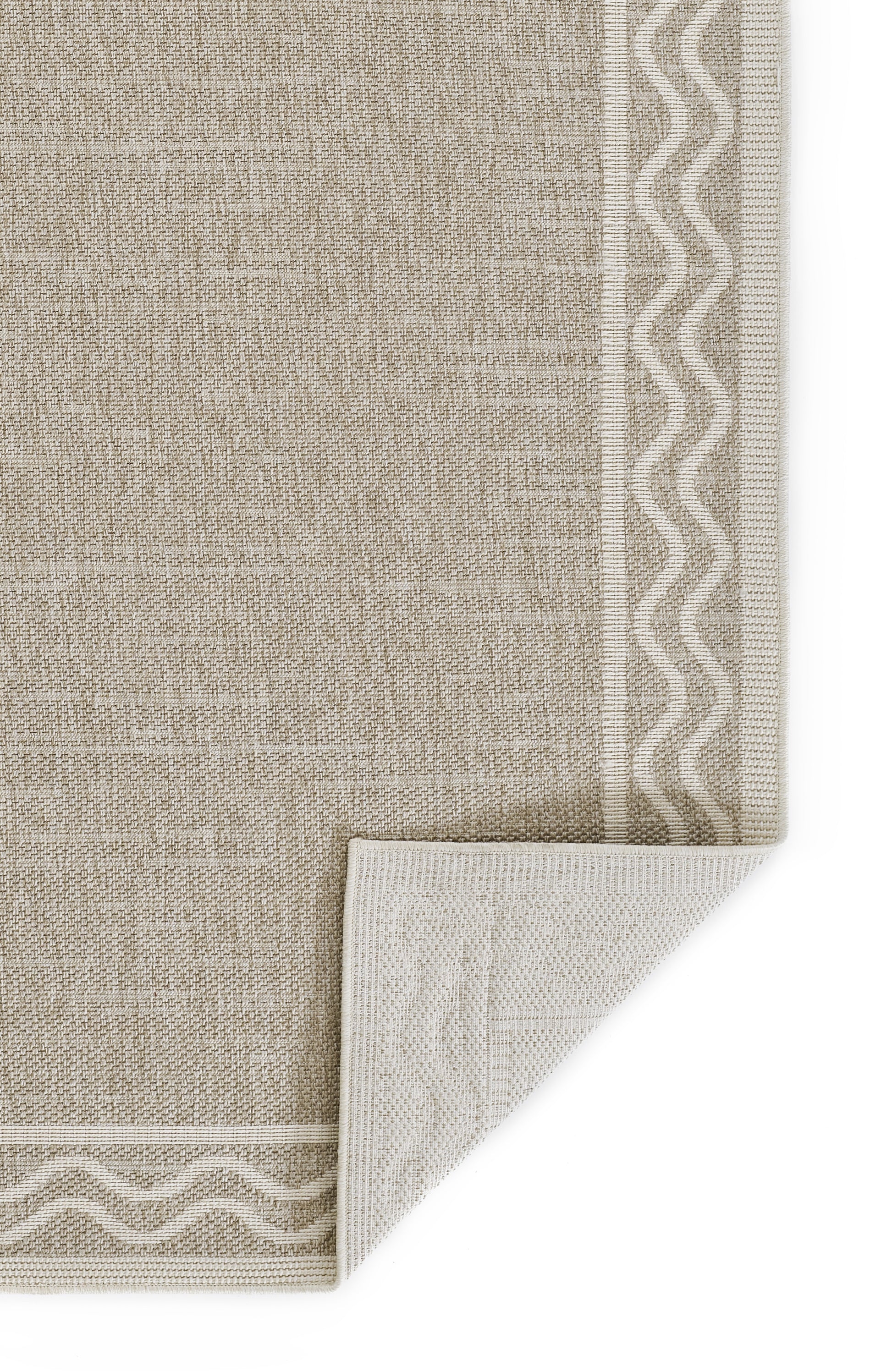Beige woven rug with white zigzag border along edges; corner folded to reveal underside.