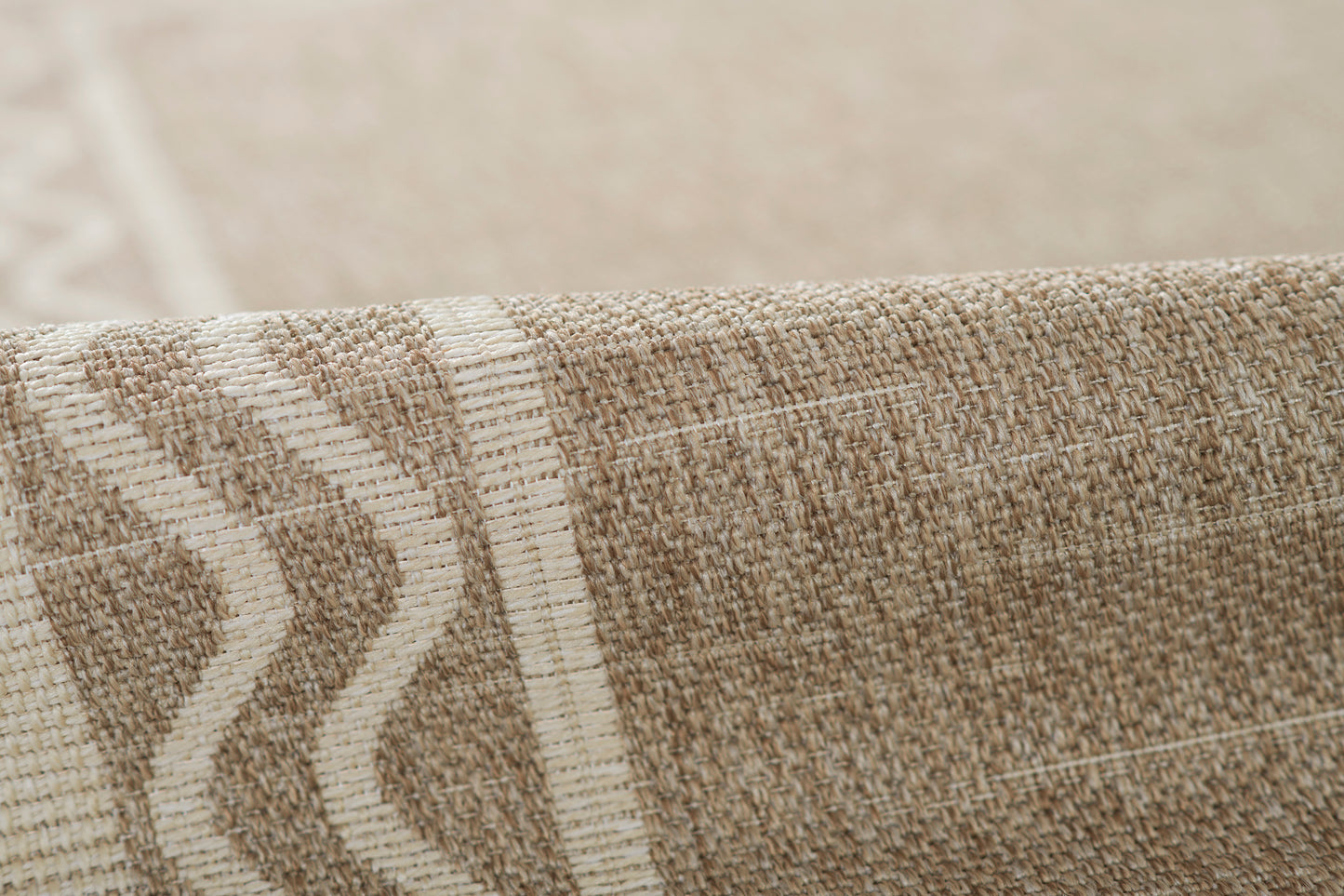 Beige and cream woven rug close-up with textured fibers and chevron stripe pattern.