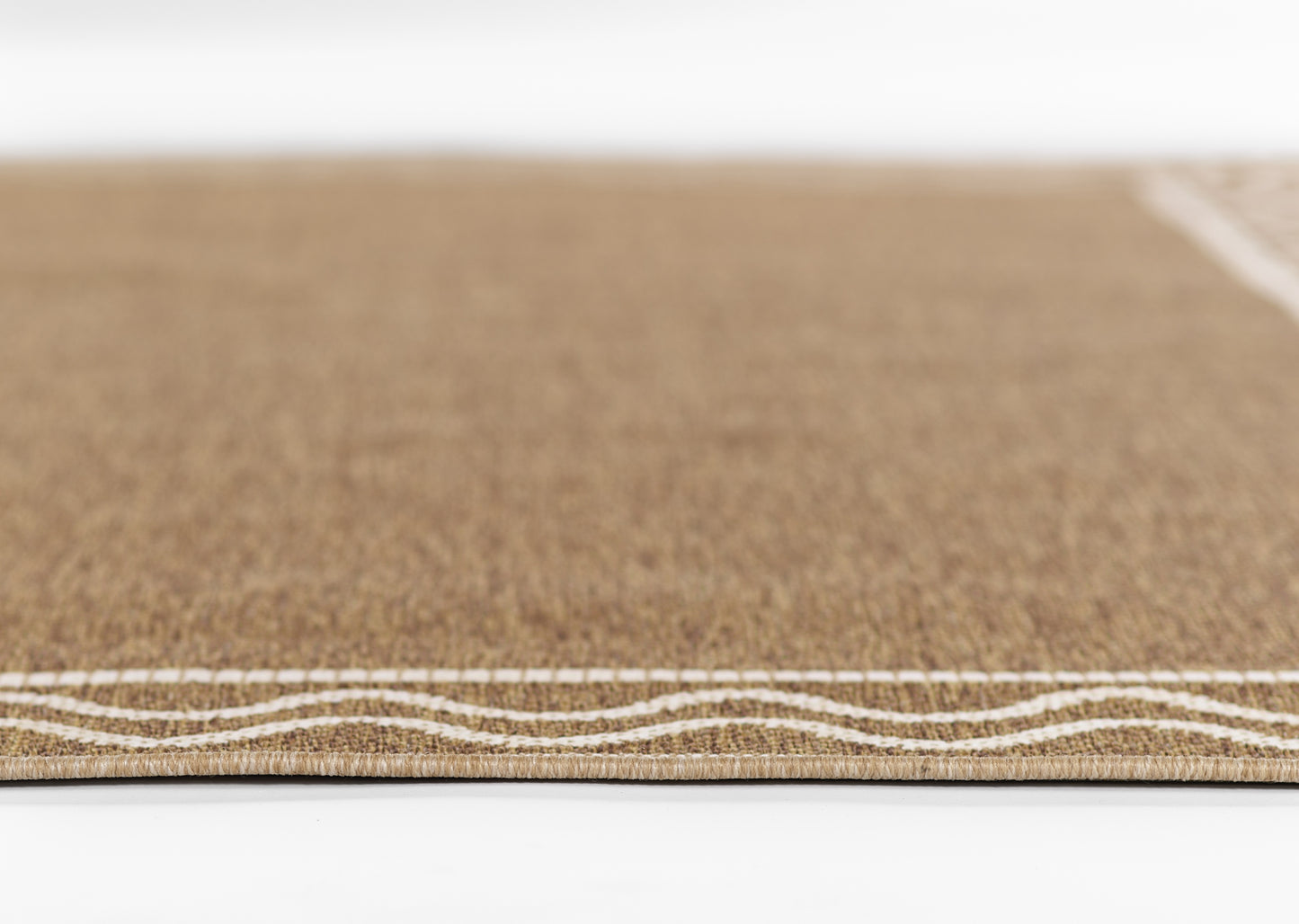 Close-up of natural beige rug (sisal/jute) with white stitched wavy border along the edge.
