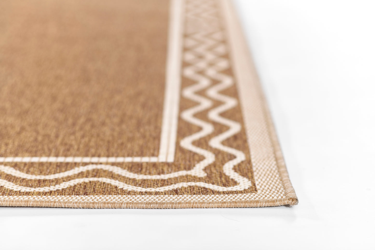 Natural brown rug with a white zigzag border and woven texture, close-up corner.