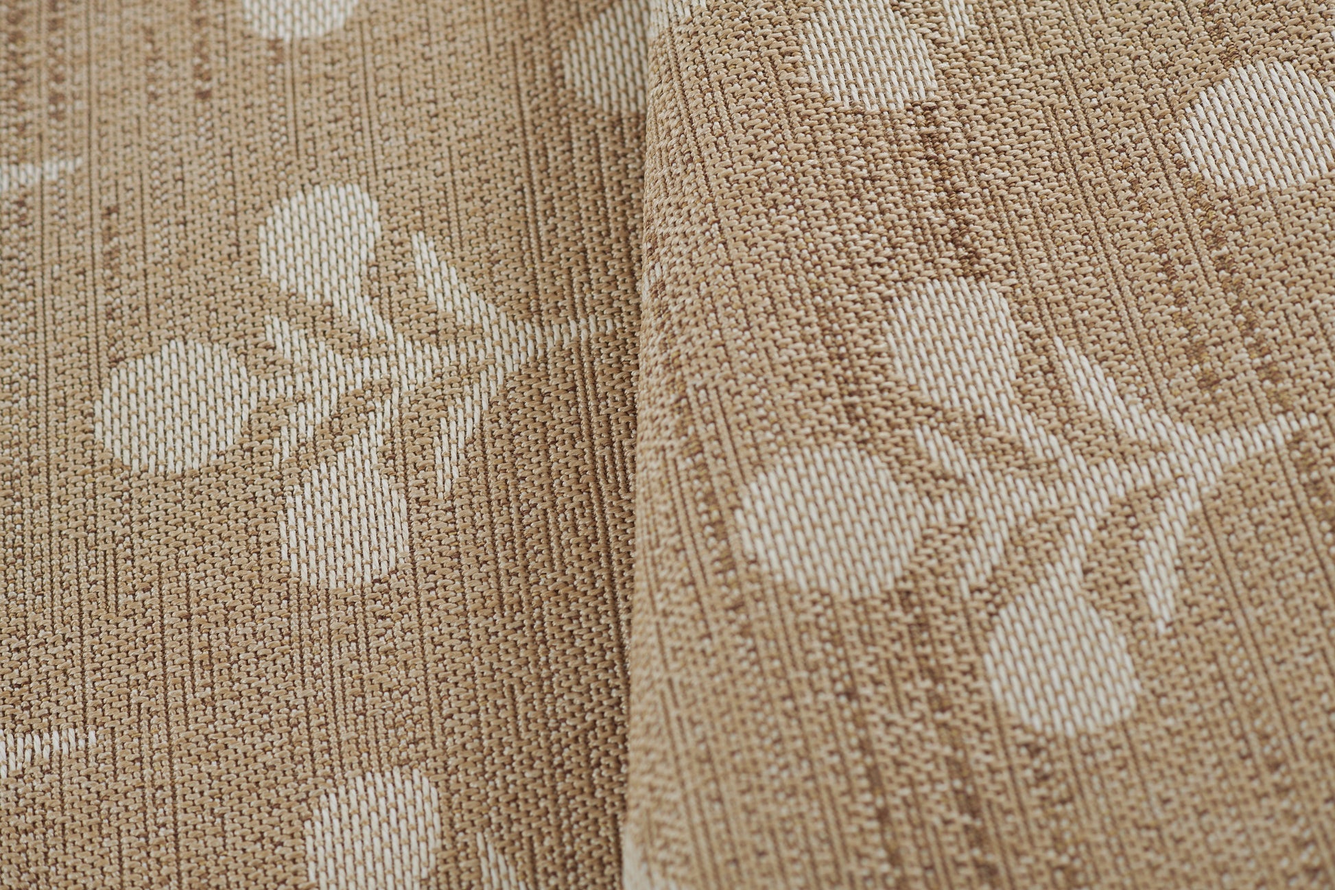 Beige textured woven rug with a white botanical leaf pattern.