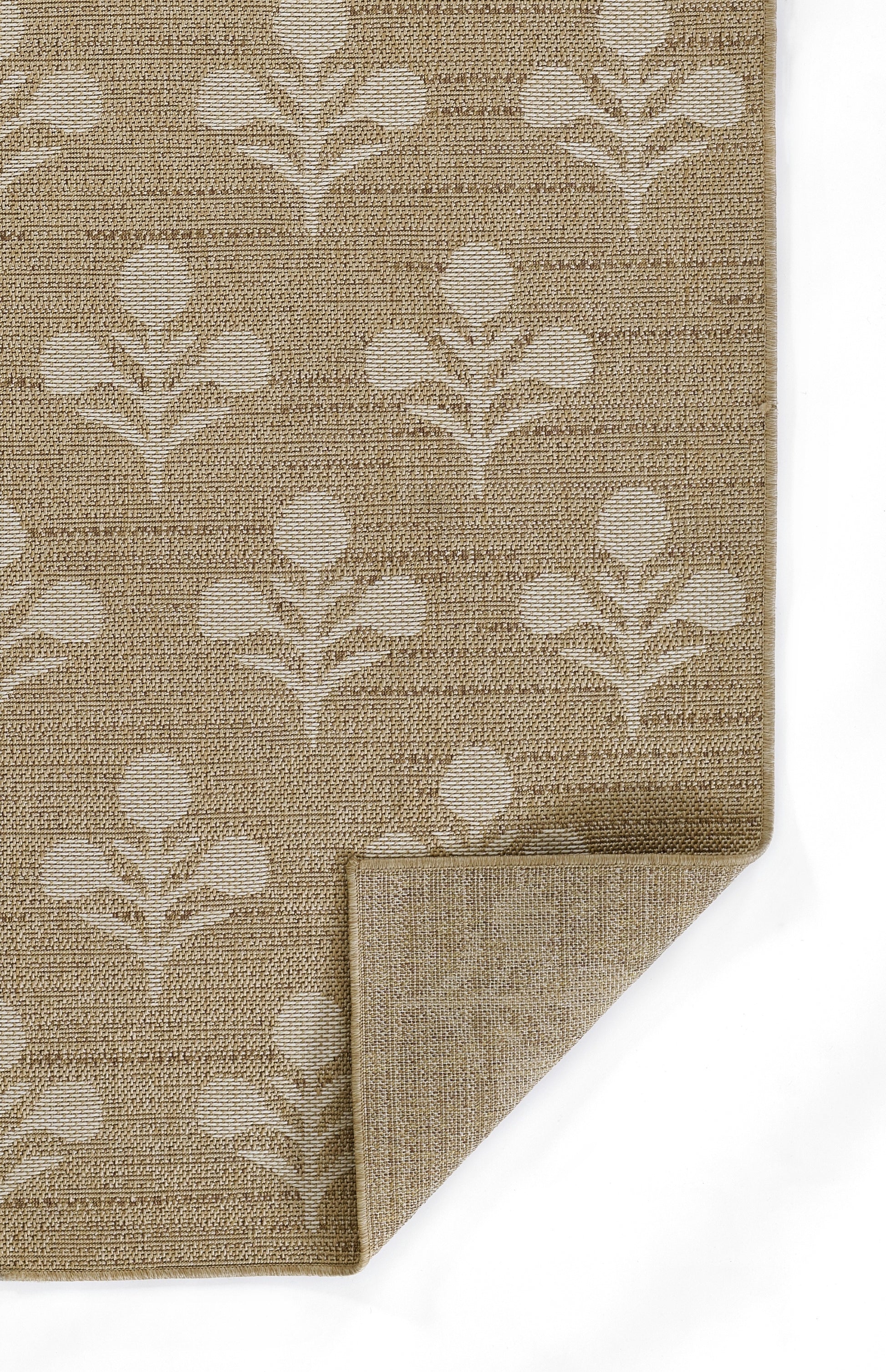 Beige woven rug with white botanical leaf motif; rectangular with folded corner.