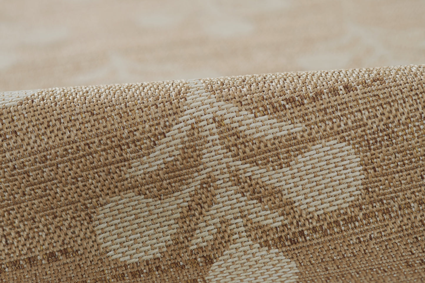 Beige jacquard rug close-up showing a subtle floral leaf motif and textured weave.