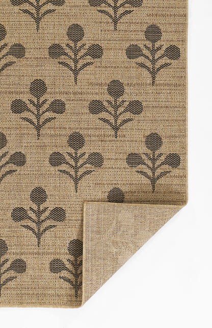 Beige woven rug with dark brown botanical leaf pattern; rectangular, folded corner reveals back.