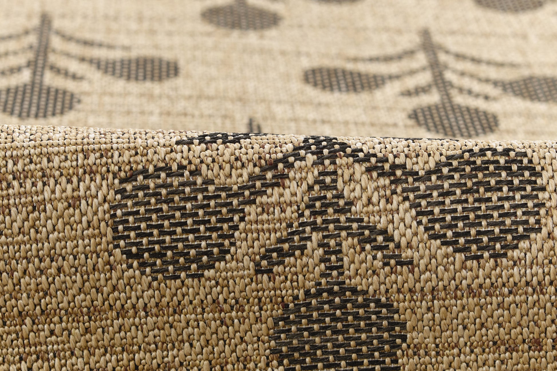 Beige woven rug with black geometric motifs and textured jute-like weave.