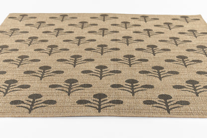 Natural jute area rug with repeating black botanical motifs; rectangular, textured weave.