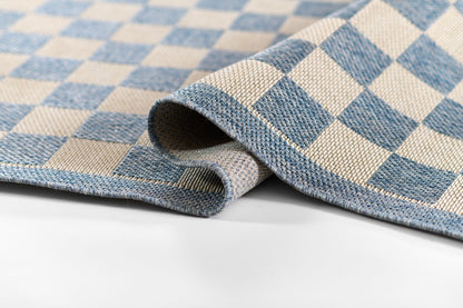 Blue and ivory checker woven rug, folded corner, displaying textured textile and bold square pattern.