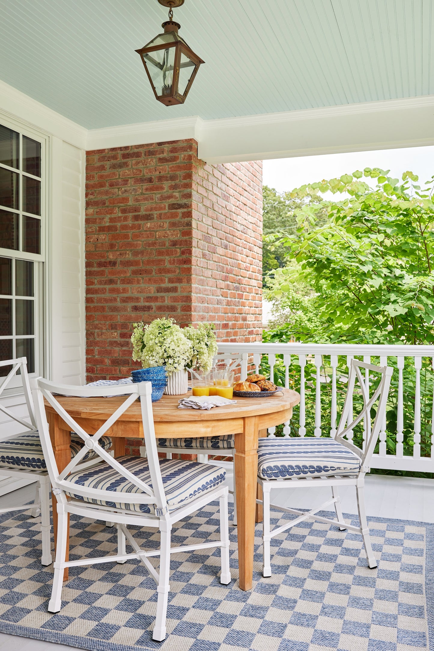 Outdoor rug runner, 2' x 8', blue tones, laid on a brick-column veranda.