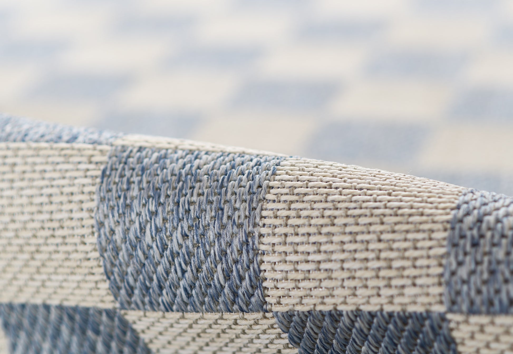 Close-up of blue and beige woven checkered rug texture; runner.
