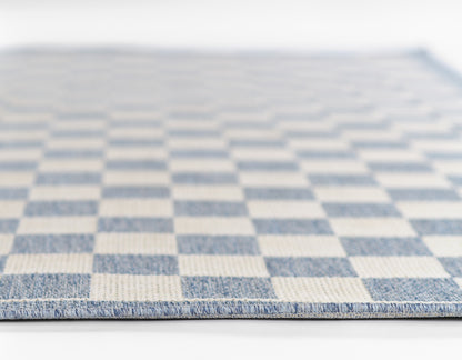 Blue and white checkerboard flatwoven rug with visible woven texture and bound edge.