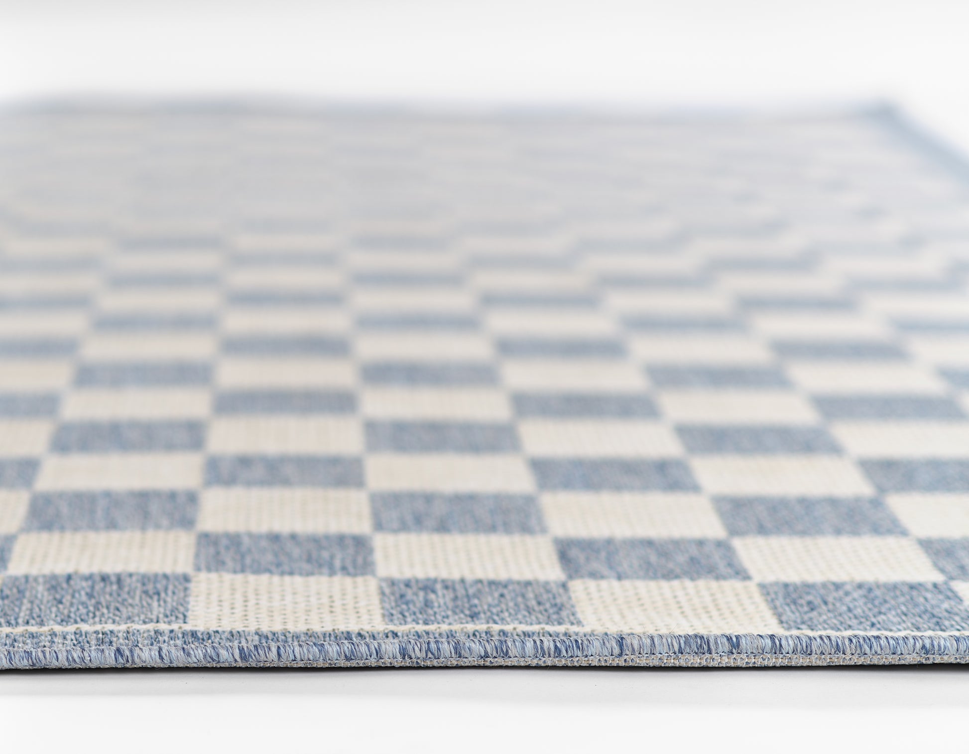 Blue and white checkerboard woven rug, rectangular floor mat with textured border.