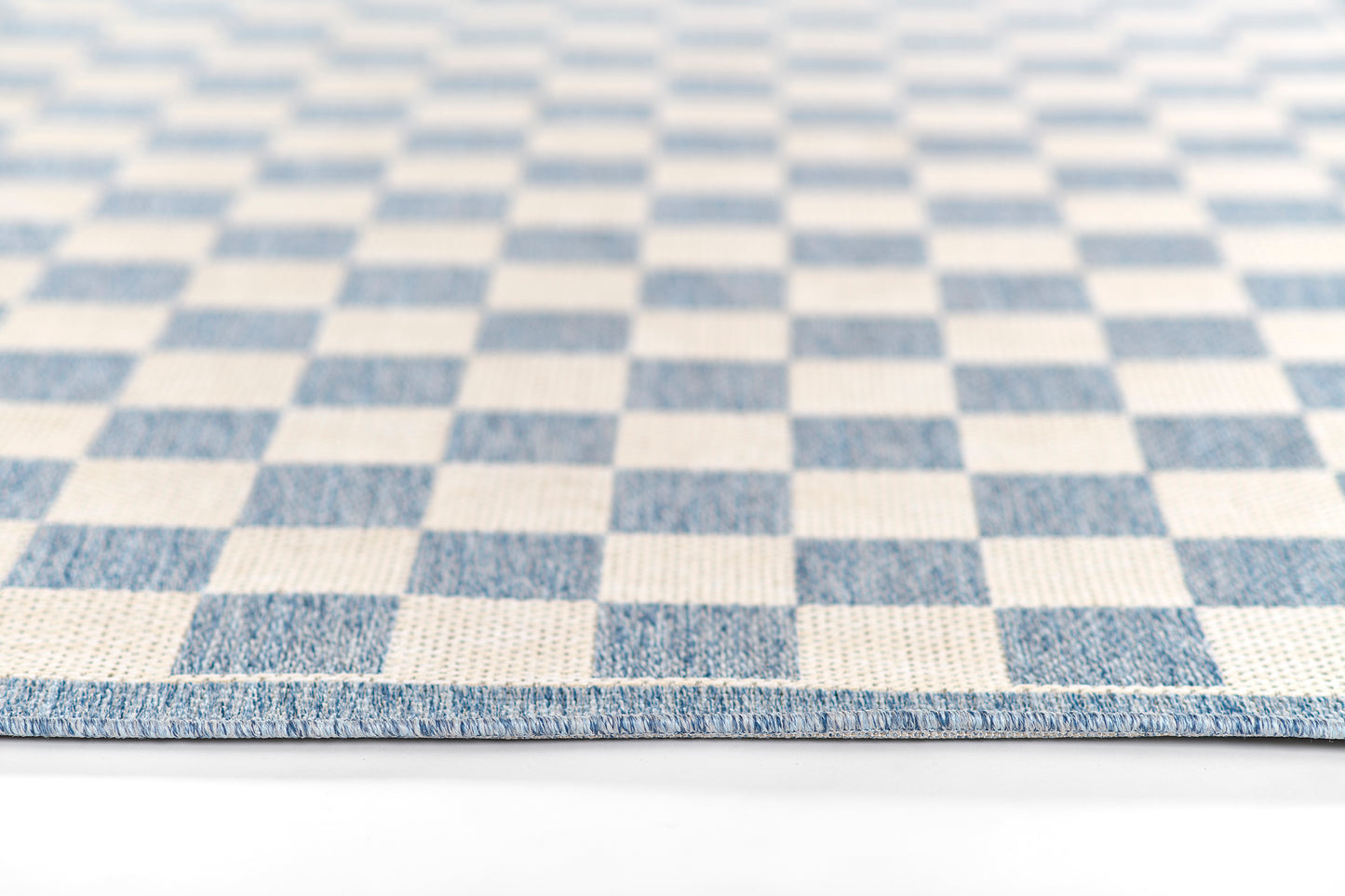 Blue and white checkerboard rug with bound edge; modern geometric floor decor for living room.