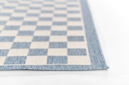Blue and white checkerboard rug, denim-blue bordered edge, woven texture.