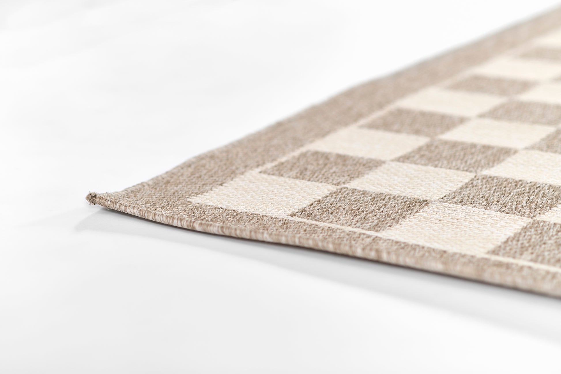 Beige and taupe checkerboard rug corner with soft woven texture, rectangular living-room rug.