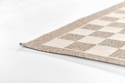 Beige and taupe checkerboard rug corner with soft woven texture, rectangular living-room rug.