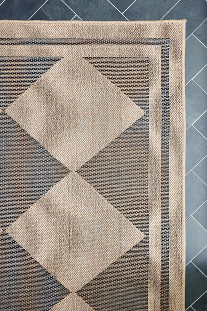 Rectangular woven rug with large beige diamond pattern and layered beige borders on blue tiled floor.