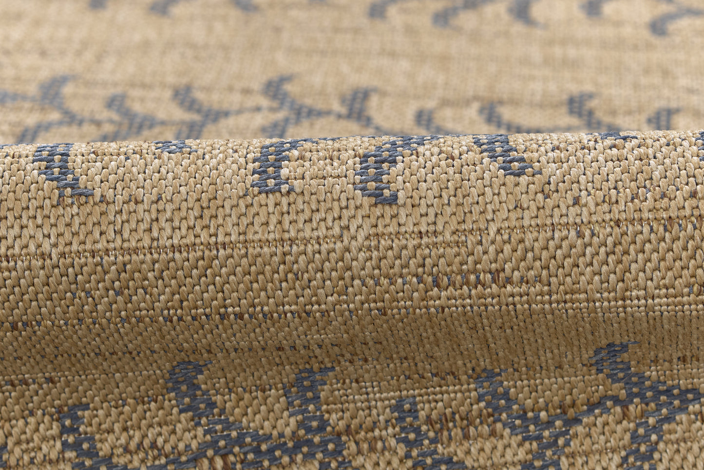 Beige woven rug with blue geometric pattern, textured jute-like fibers, rolled edge.