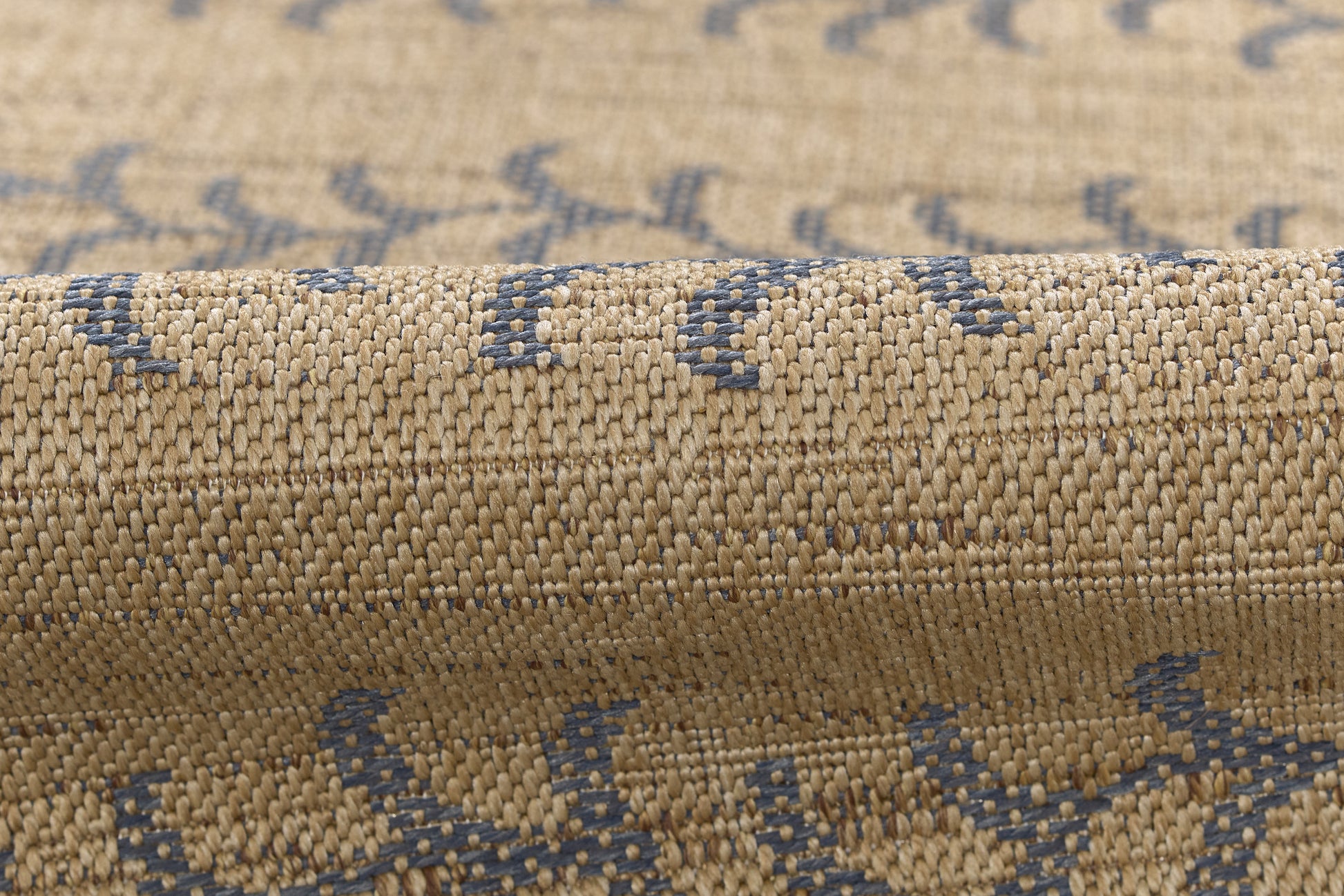 Beige woven rug with blue geometric pattern, textured jute-like fibers, rolled edge.