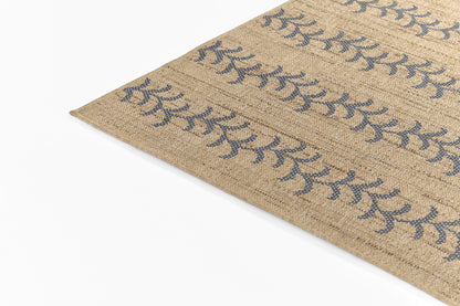 Natural jute rug with blue botanical motifs, woven texture, beige background, corner edge visible.