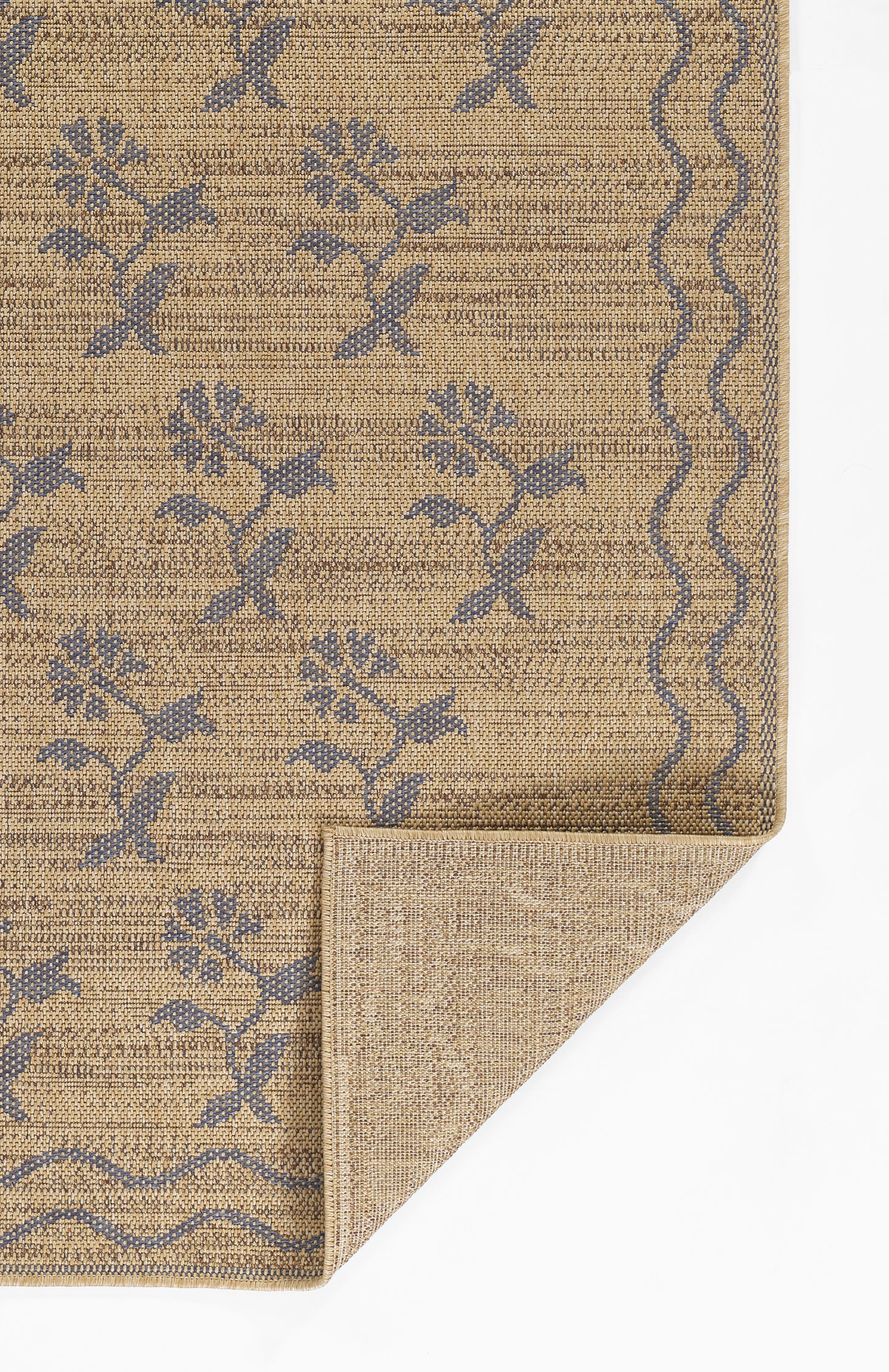 Beige woven rug with blue floral vine pattern, bound edges and wavy border; folded corner reveals back.
