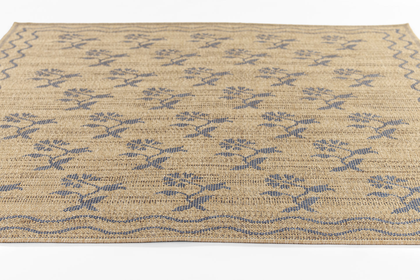 Rectangular natural jute runner rug in beige with navy blue geometric floral motifs and a wavy border.