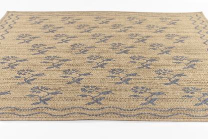 Beige jute woven rug with blue floral motifs and a blue wavy border, rustic coastal style.