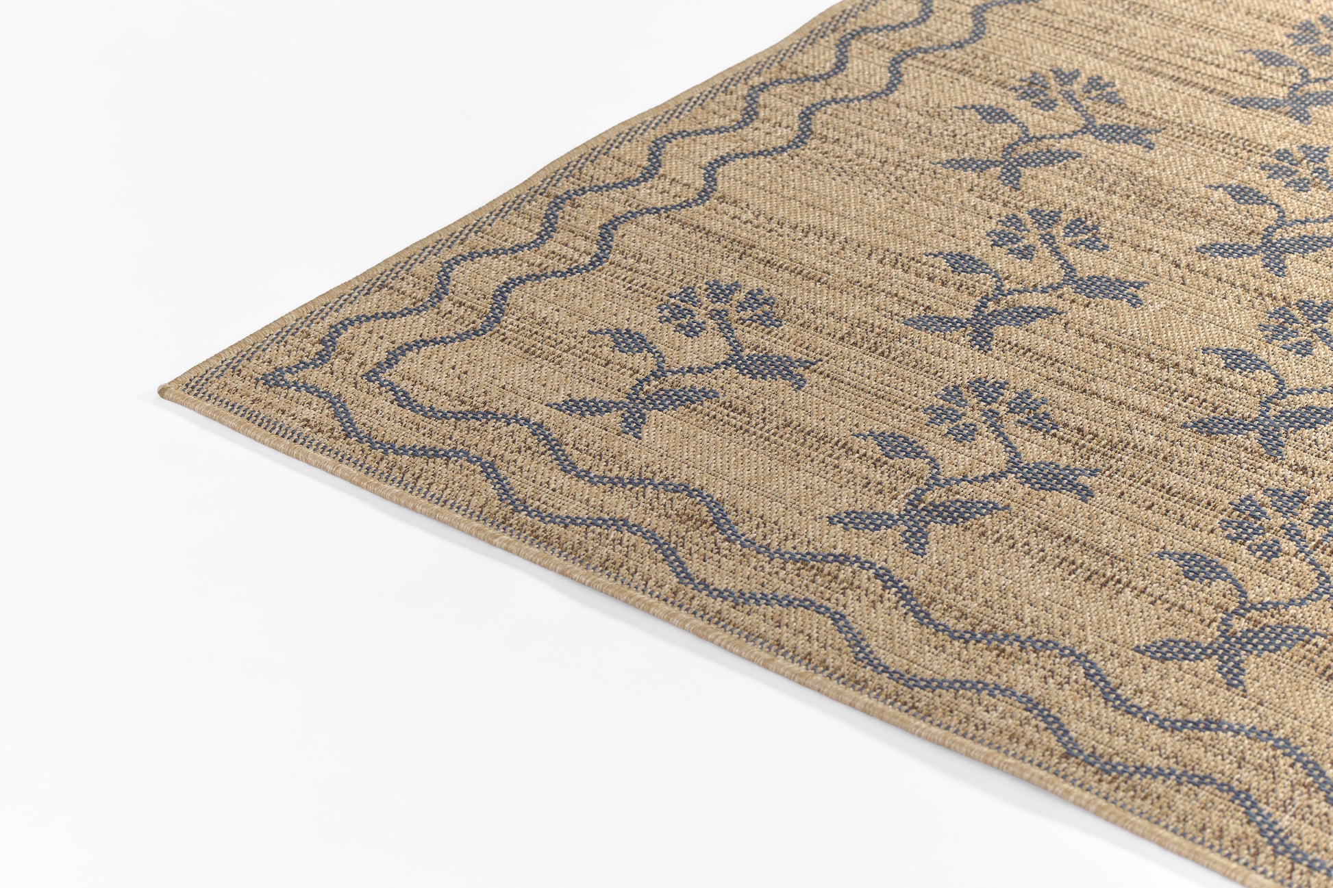 Beige woven rug with blue floral motifs and wavy blue border; natural textured surface.