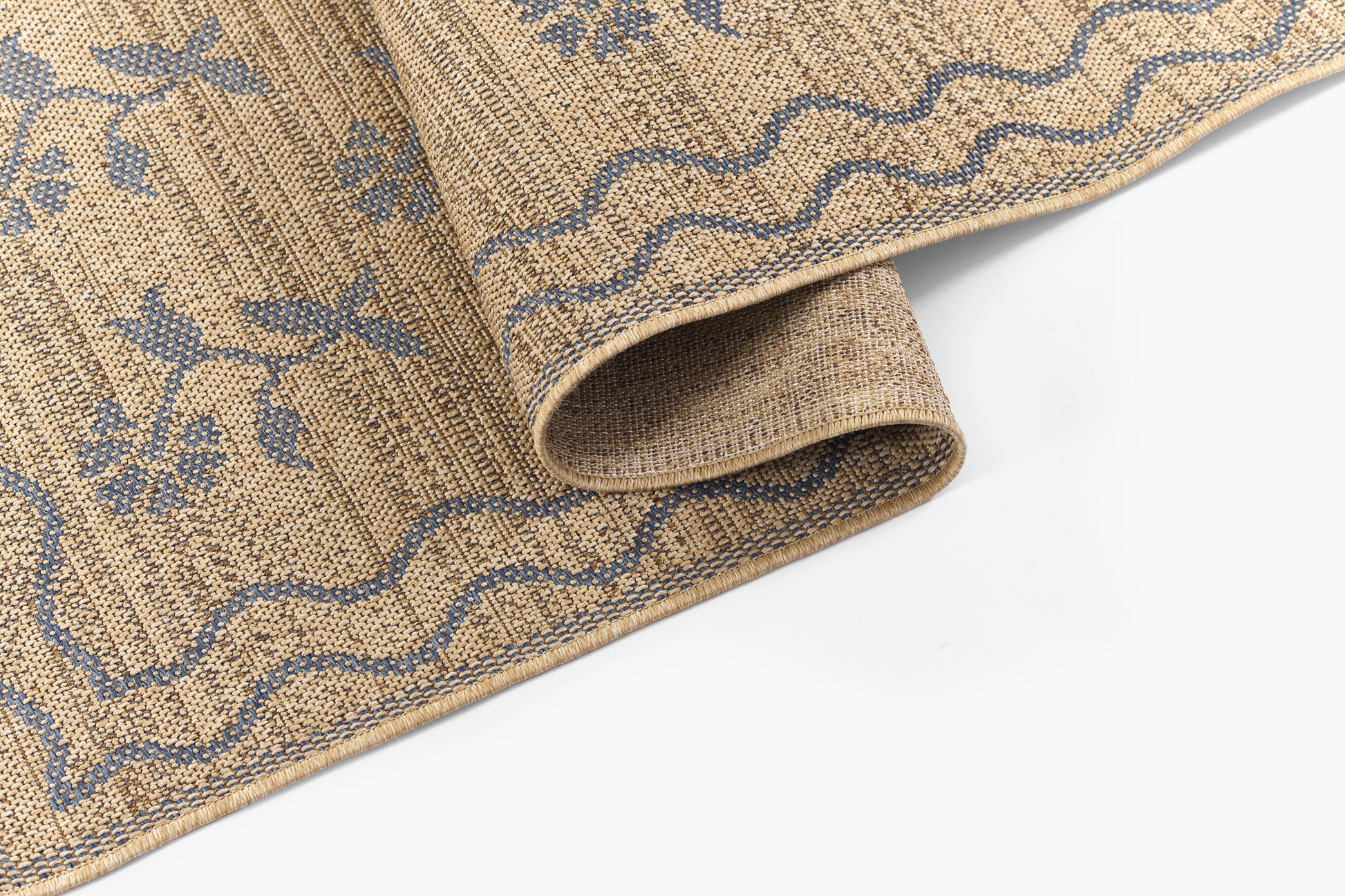 Beige jute rug with blue floral vines and wavy border, thick woven texture, rolled corner.