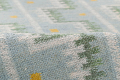 Close-up of blue & white woven runner with geometric Scandinavian pattern, green & yellow accents & soft textured pile.
