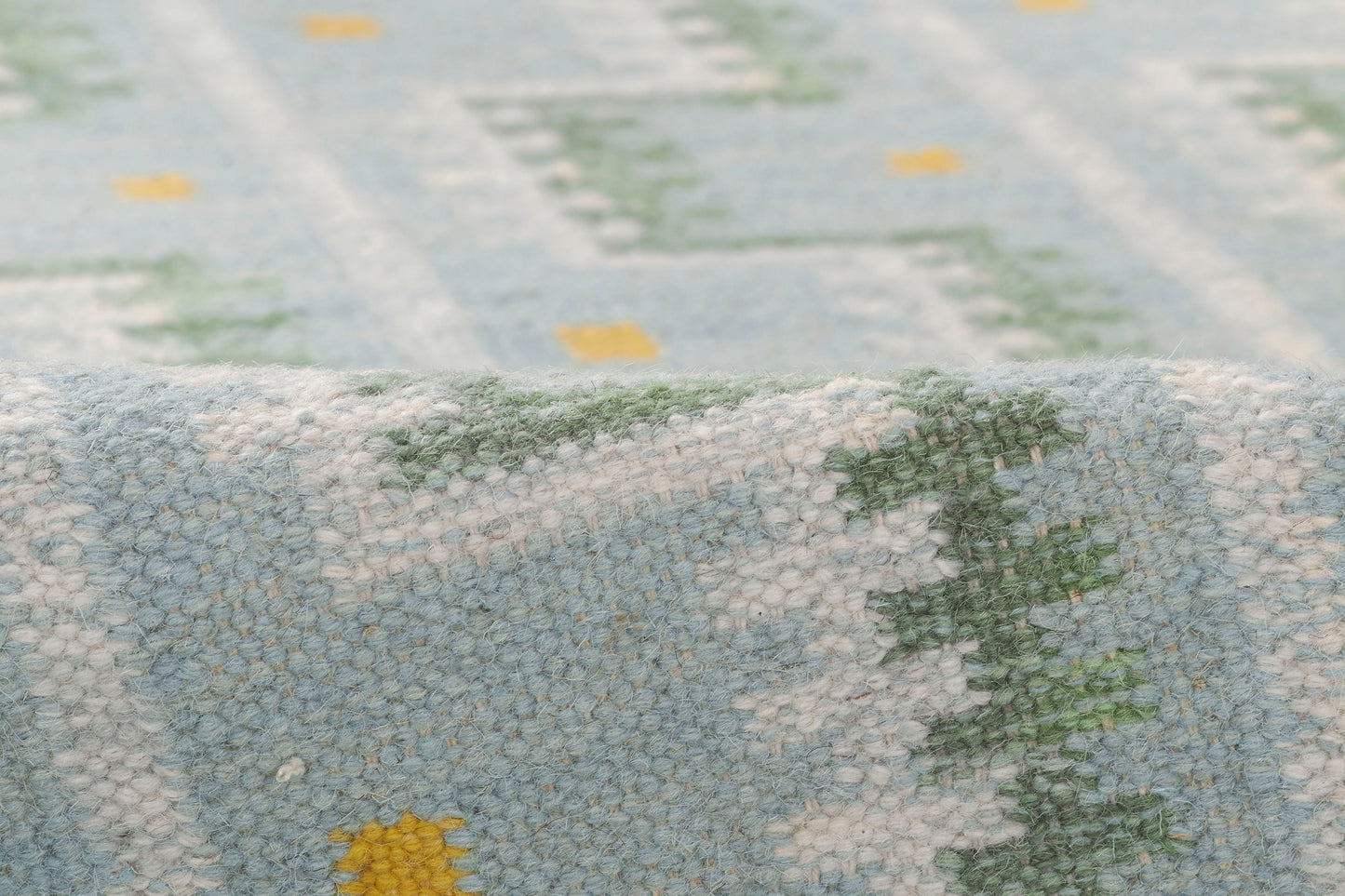 Soft blue boucle rug with white and green Nordic geometric pattern and folded edge.