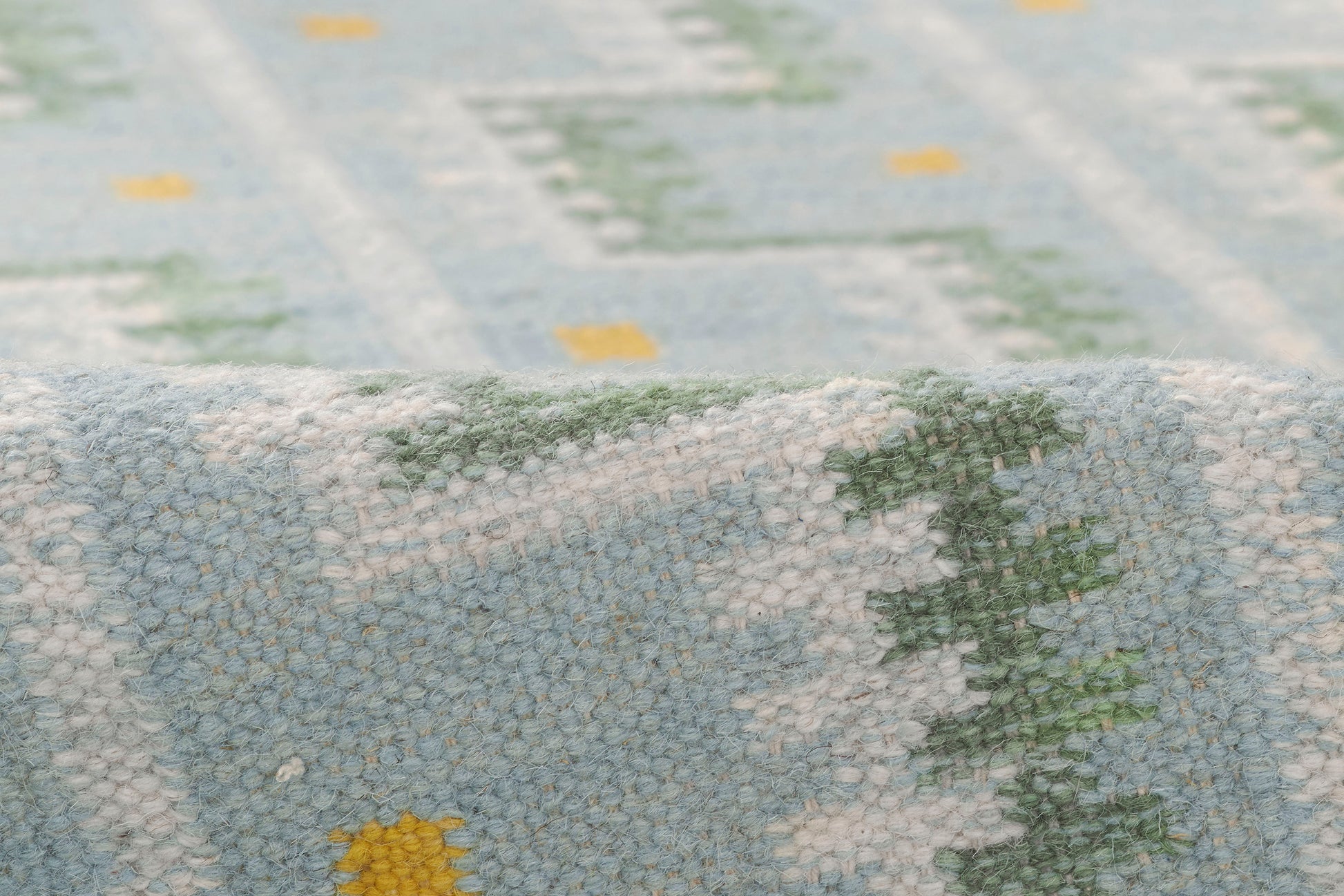 Soft blue boucle rug with white and green Nordic geometric pattern and folded edge.